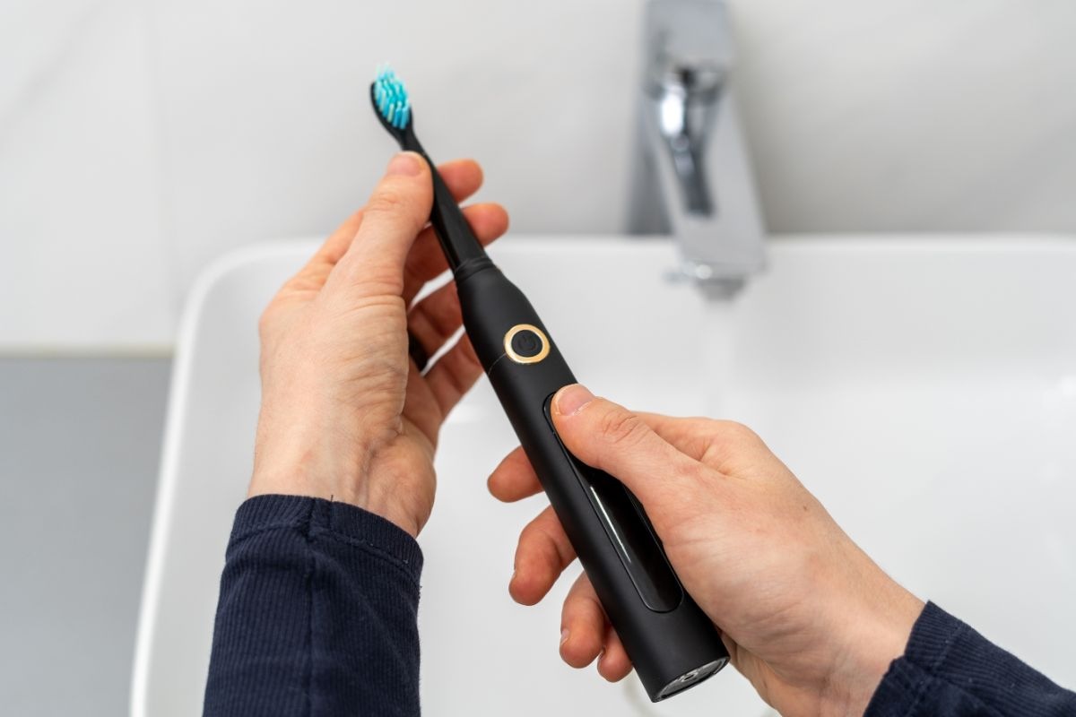 uomo che mantiene spazzolino elettrico
