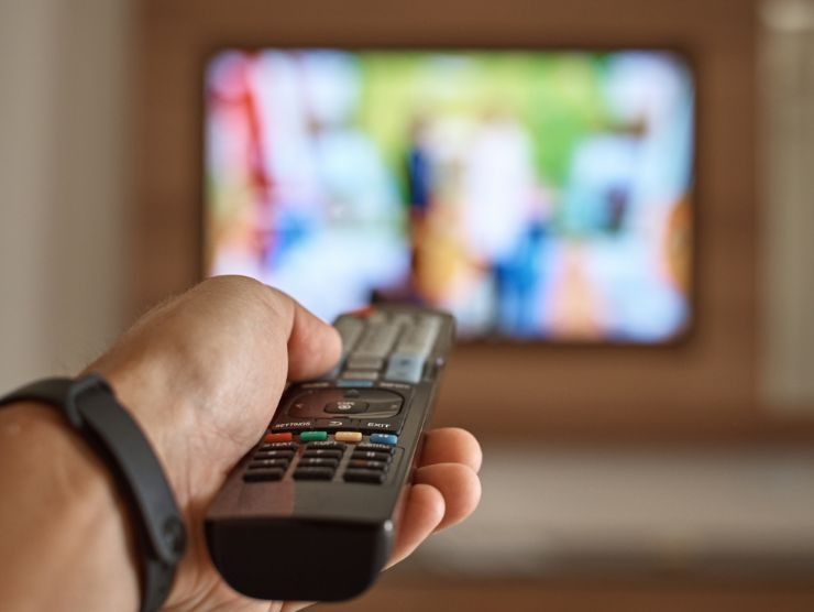 uomo che usa telecomando per cambiare canale