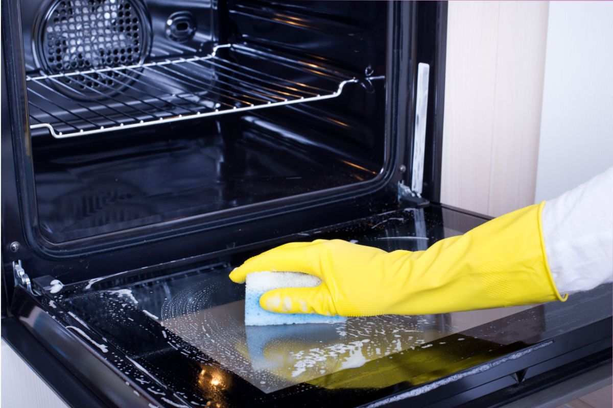 mano che pulisce vetro del forno